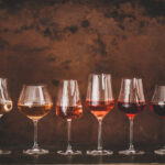 Shades of Rose wine in glasses, rusty background, copy space