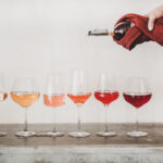 Rose wine shades and womans hand pouring wine to glass